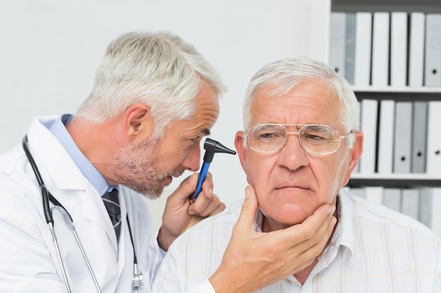 Primo piano di un medico maschio che esamina l&#39;orecchio del paziente senior