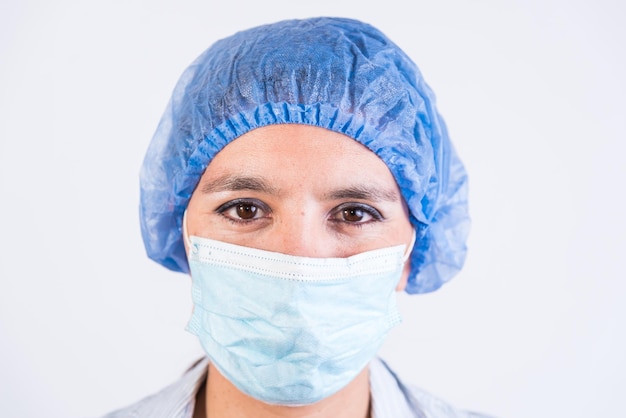 Primo piano di un medico serio con berretto e maschera medici che indagano su un'infezione