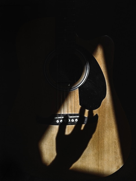 Primo piano di un'ombra della mano che strimpella sulle corde della chitarra