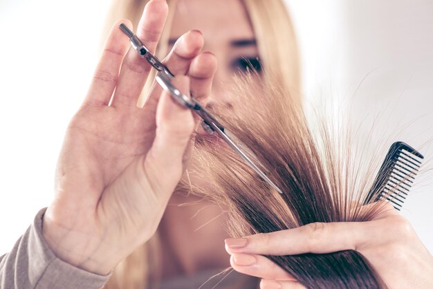 Primo piano di un parrucchiere che taglia i capelli di una donna. Messa a fuoco selettiva.