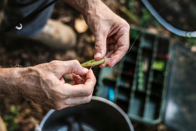 Primo piano di un pescatore che mette esca