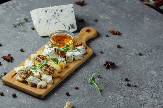 Primo piano di un piatto di formaggi. 4 tipi di formaggio, brie bianco a pasta molle, camembert, briques semimorbida, blu, roquefort, formaggio a pasta dura. Noci, uva verde. Bellissimo servizio. ristorante.