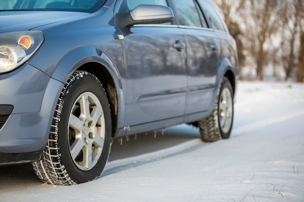 Primo piano di un pneumatico per auto parcheggiato su strada innevata durante la giornata invernale. Trasporto e concetto di sicurezza.