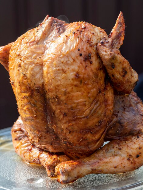 Primo piano di un pollo succoso brillante in spezie cotto interamente alla griglia. Sfondo verde sfocato. immagini orizzontali