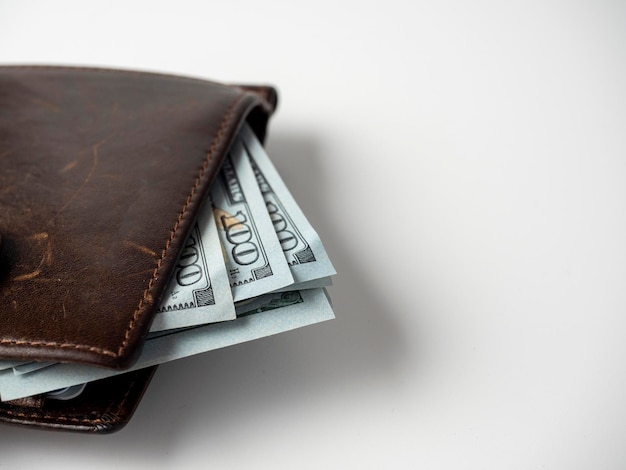 Primo piano di un portafoglio in pelle marrone farcito con banconote da un dollaro su sfondo bianco. Il concetto di ricchezza, profitto, ricchezza. Copia spazio