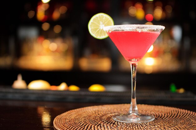 Primo piano di un rinfrescante cocktail margarita rosa sul bancone di un bar