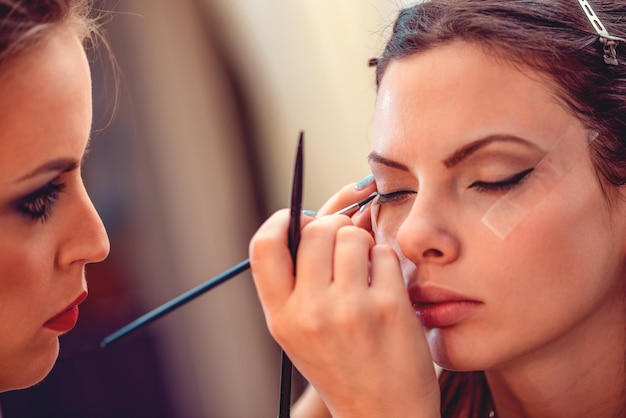 Primo piano di un truccatore che applica l'eyeliner a un modello.