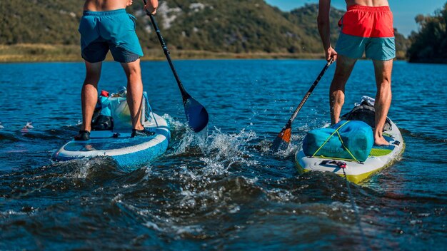 primo piano di un uomo che fa paddleboard in acque blu trasparenti con attrezzature di sicurezza a bordo