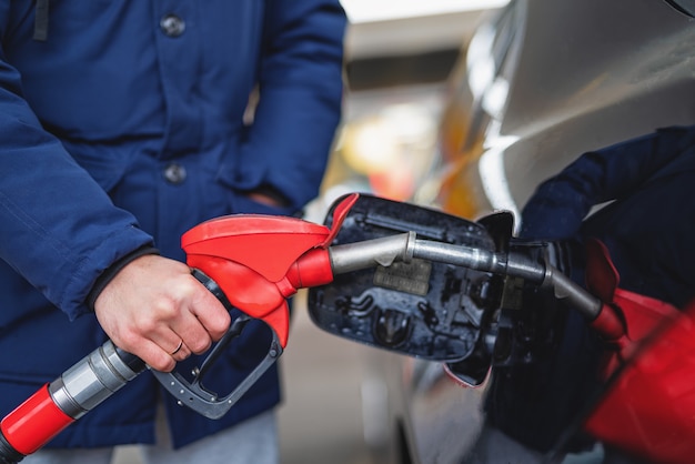 Primo piano di un uomo che pompa benzina in un'auto in una stazione di servizio.