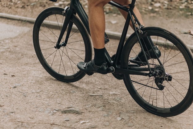 Primo piano di un uomo con gambe muscolose in sella a una bici nera