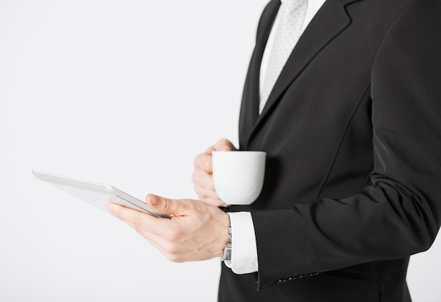 primo piano di un uomo con un tablet pc e una tazza di caffè