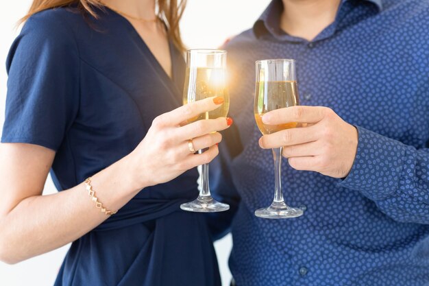 Primo piano di un uomo e di una donna che celebrano la festa di Natale o Capodanno con luci bengala e bicchieri di champagne.