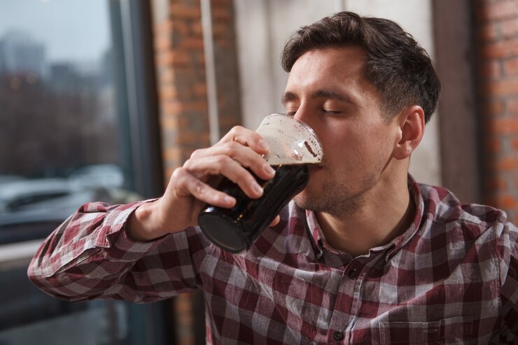 Foto primo piano di un uomo sorseggiando una gustosa birra artigianale con gli occhi chiusi per il piacere