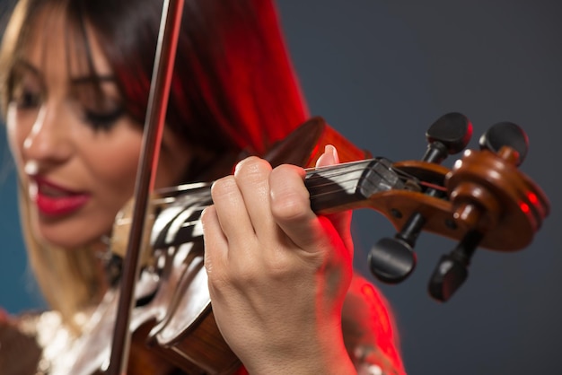 Primo piano di un violino suonato da una giovane donna con la faccia sfocata.