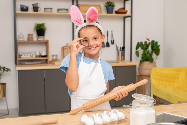 Primo piano di una bambina che cerca la ricetta dell'insalata su una tavoletta digitale mentre si trova al tavolo da cucina in legno