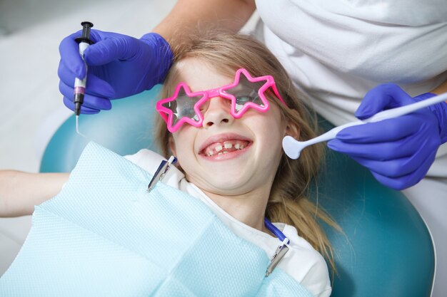 Primo piano di una bambina felice che sorride alla telecamera durante il controllo dentale