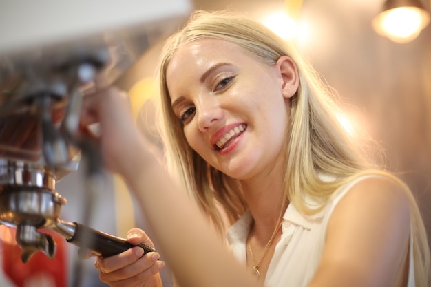 Primo piano di una bella donna che usa la macchina per il caffè in cucina