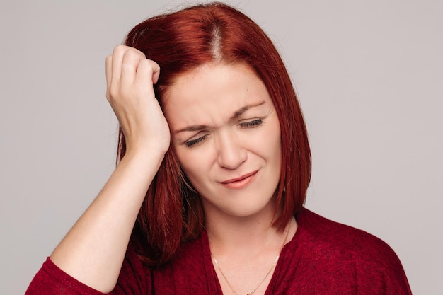 Primo piano di una bella donna dai capelli rossi in blusa di bordo con mal di testa