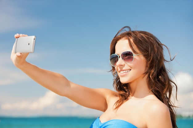 primo piano di una bella donna sulla spiaggia con il telefono