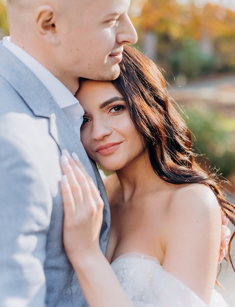 Primo piano di una bella sposa bruna che abbraccia il suo amante e guarda la telecamera