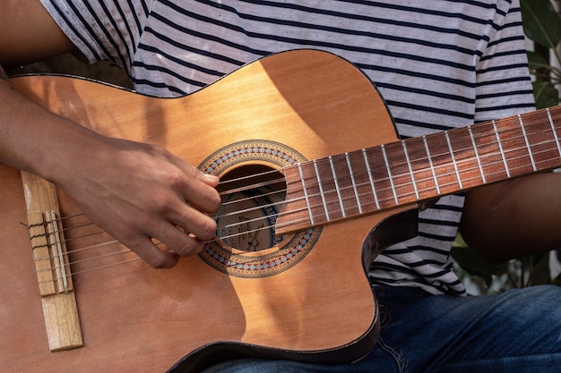 Primo piano di una chitarra acustica spagnola e delle mani del chitarrista che strimpellano le corde