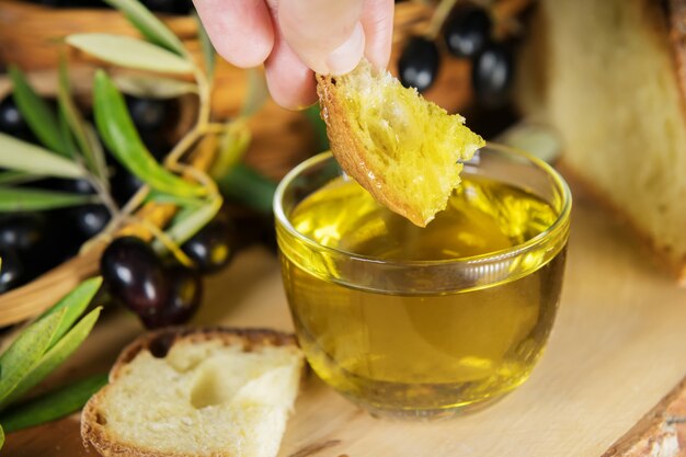 Primo piano di una ciotola di vetro piena di olio d'oliva con pane e brunch di olive. grassi sani