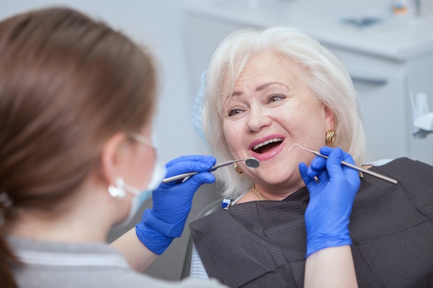 Primo piano di una donna anziana allegra che ha un esame dentale dal suo dentista