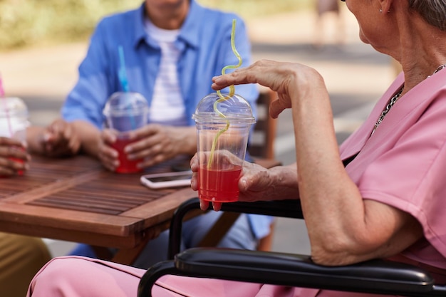 Primo piano di una donna anziana che si diverte a bere un drink al caffè all'aperto