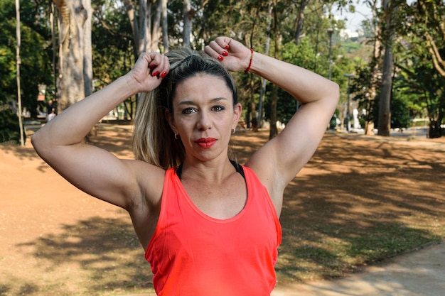 Primo piano di una donna brasiliana, in abiti da allenamento, che tiene i capelli sulle scale di cemento in una piazza pubblica.