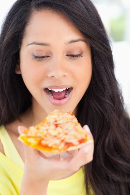Primo piano di una donna che guarda la fetta di pizza che sta per mangiare