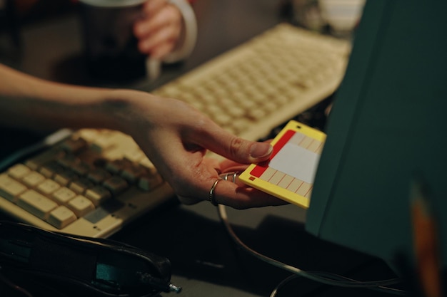 Primo piano di una donna che inserisce il dischetto nel computer per proteggere le informazioni durante il suo lavoro sul PC desktop