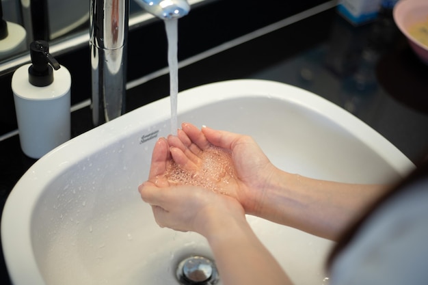 Primo piano di una donna che si lava le mani in bagno per prevenire l'infezione virale Covid19