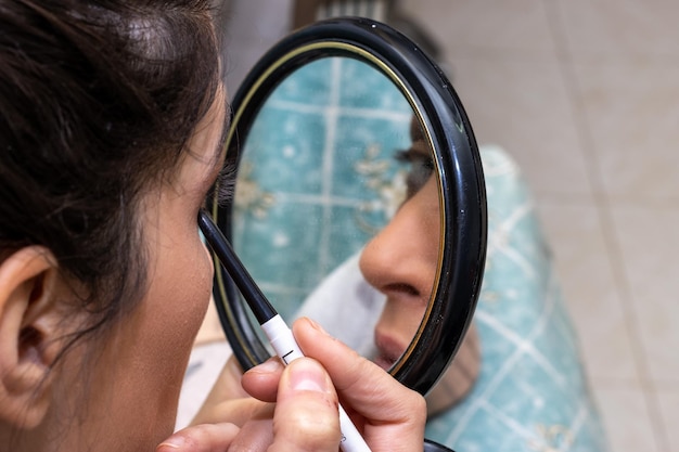 Primo piano di una donna che si trucca con uno specchietto a casa bellezza e immagine personale