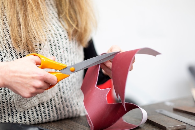 primo piano di una donna che taglia con le forbici un pezzo di pelle primo piano