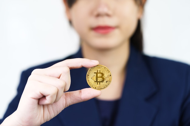 Primo piano di una donna che tiene in mano alcuni pezzi di token Bitcoin dorato