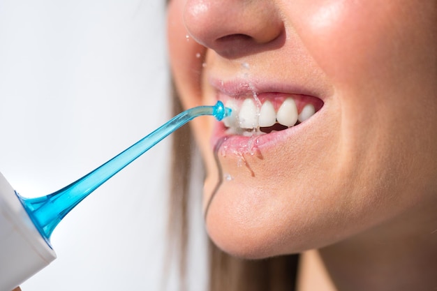 Primo piano di una donna con un sorriso perfetto che usa l'idropulsore o un irrigatore orale
