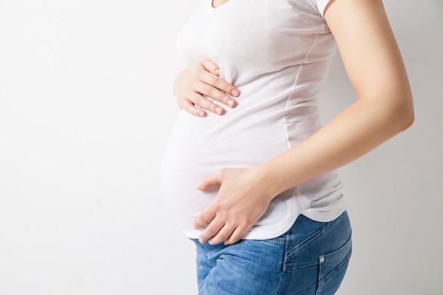 Primo piano di una donna con una maglietta bianca in attesa di un bambino