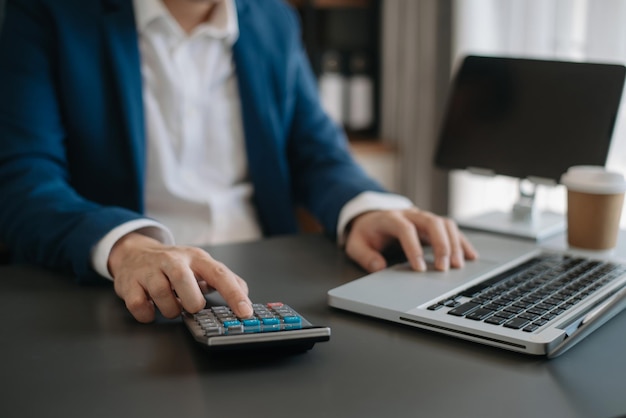 Primo piano di una donna d'affari o di un contabile che digita a mano un computer portatile che lavora per calcolare sulla scrivania i costi in ufficio a casa