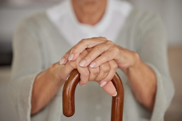 Primo piano di una donna disabile con le mani degli anziani che tiene un bastone in una casa di cura