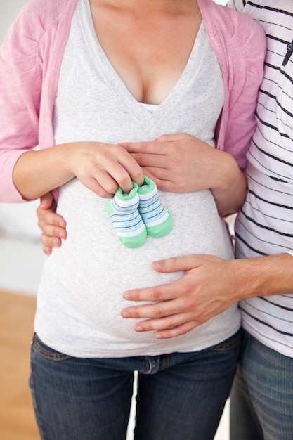 Primo piano di una donna incinta caucasica che tiene le scarpe di bambino e di suo marito