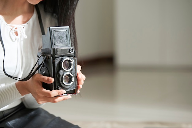 Primo piano di una donna irriconoscibile che utilizza una fotocamera vintage mentre fotografa in studio