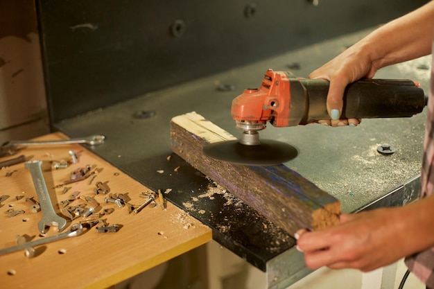 Primo piano di una donna operaia macina a mano la levigatura del legno in officina