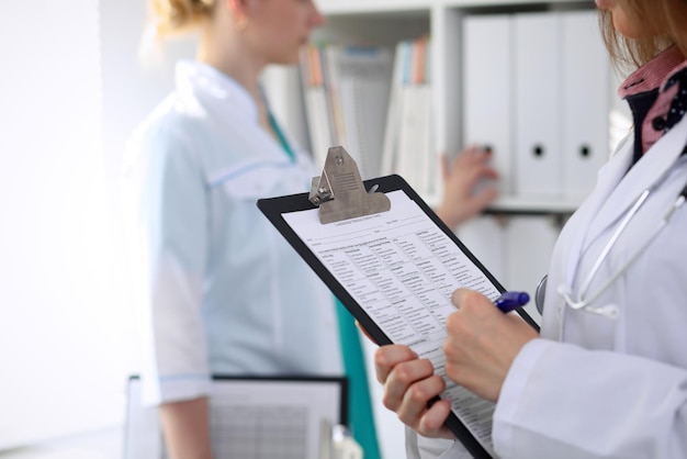 Primo piano di una dottoressa mentre compila il modulo di domanda medica.