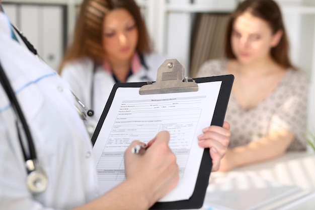 Primo piano di una dottoressa mentre riempie la cartella clinica.