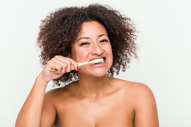 Primo piano di una giovane donna afro-americana a lavarsi i denti con uno spazzolino da denti