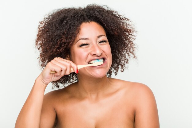 Primo piano di una giovane donna afro-americana a lavarsi i denti con uno spazzolino da denti