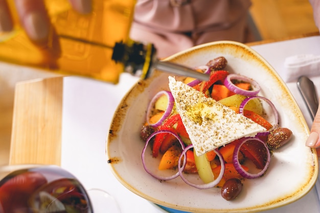 Primo piano di una giovane donna che aggiunge olio a una deliziosa insalata fresca di verdure bianche e cipolla