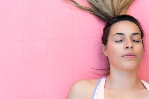 Primo piano di una giovane donna che medita su una stuoia rosa