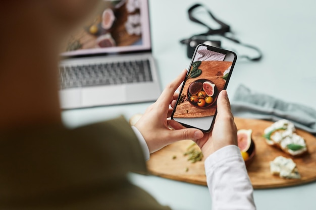 Primo piano di una giovane donna che scatta foto estetiche del cibo utilizzando lo smartphone per lo spazio di copia dei social media