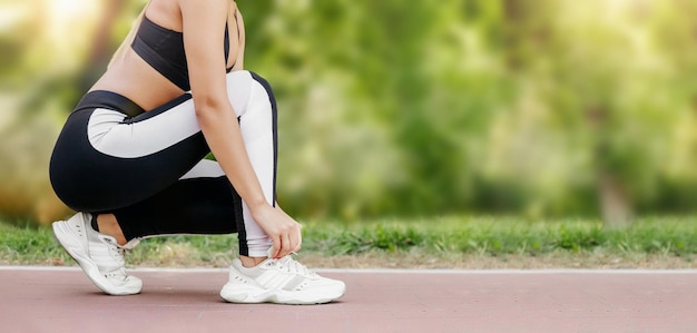 Primo piano di una giovane donna che si prepara per fare jogging all'aperto mentre si allaccia le scarpe da ginnastica